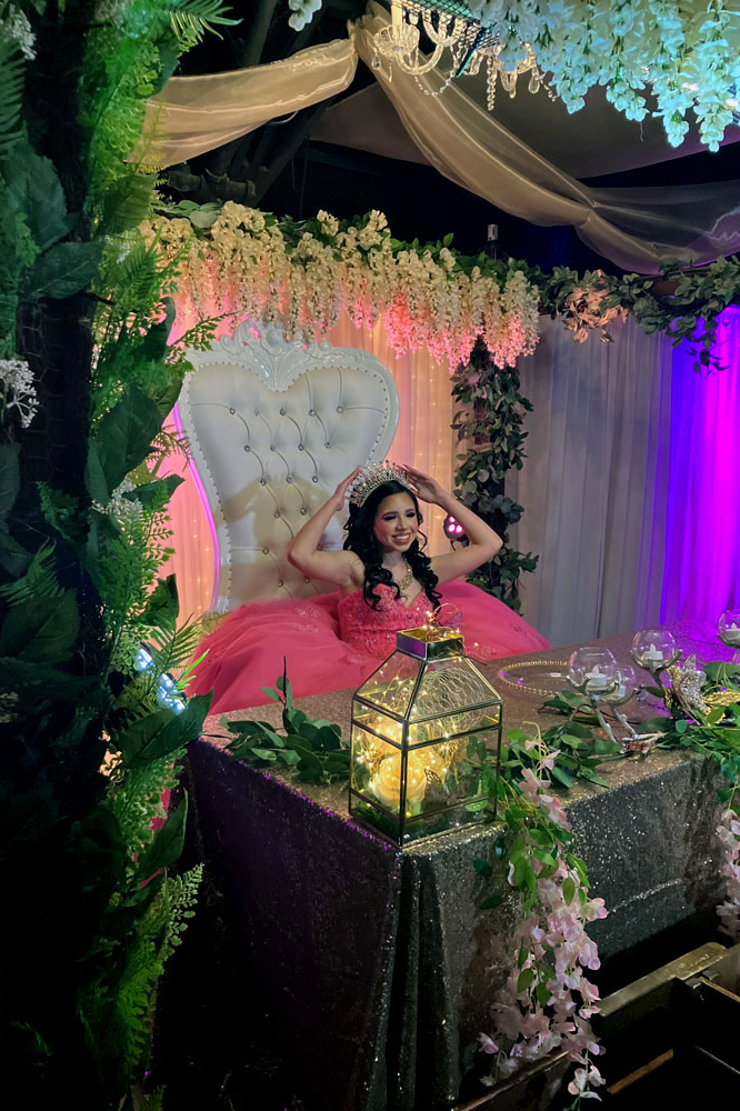 Qinceanera girl in garden gazebo on throne chair.