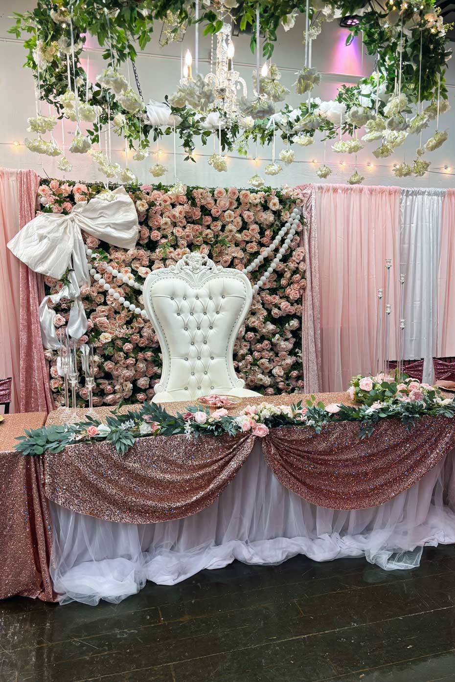 Table of honor with fabric, roses, and bows background.