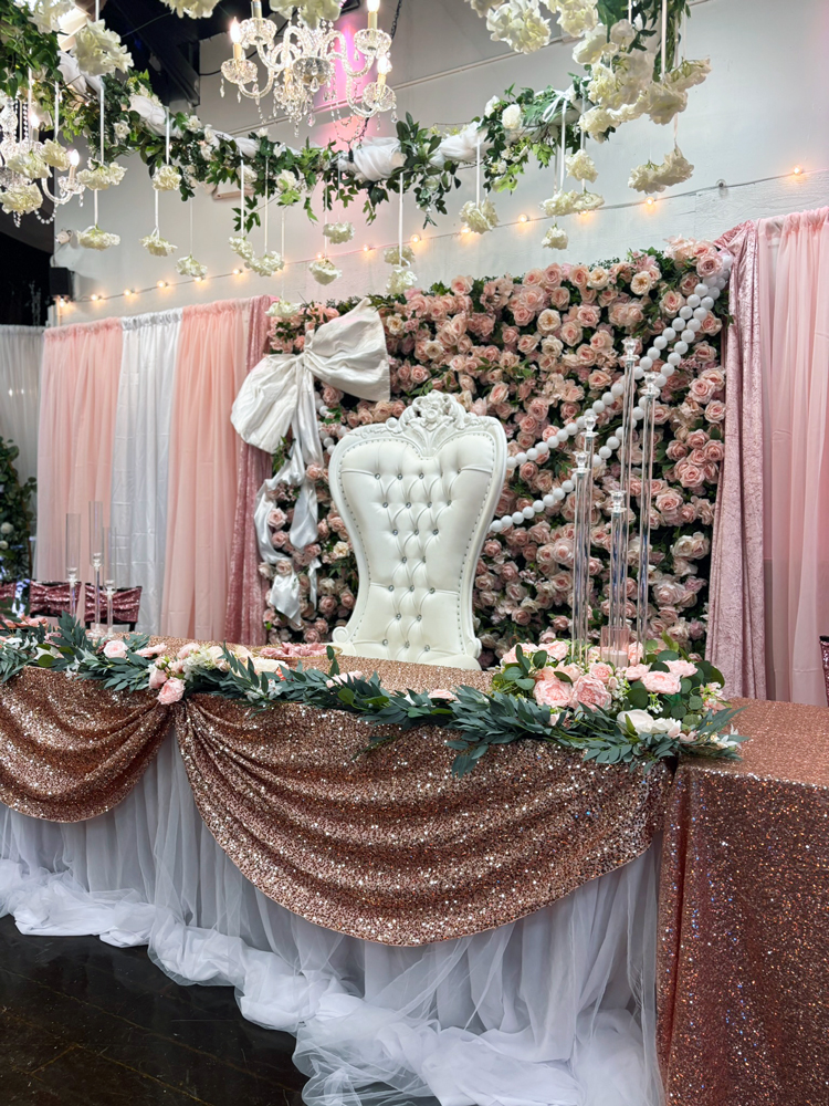 Throne chair at a decorated table of honor in front of a flower wall