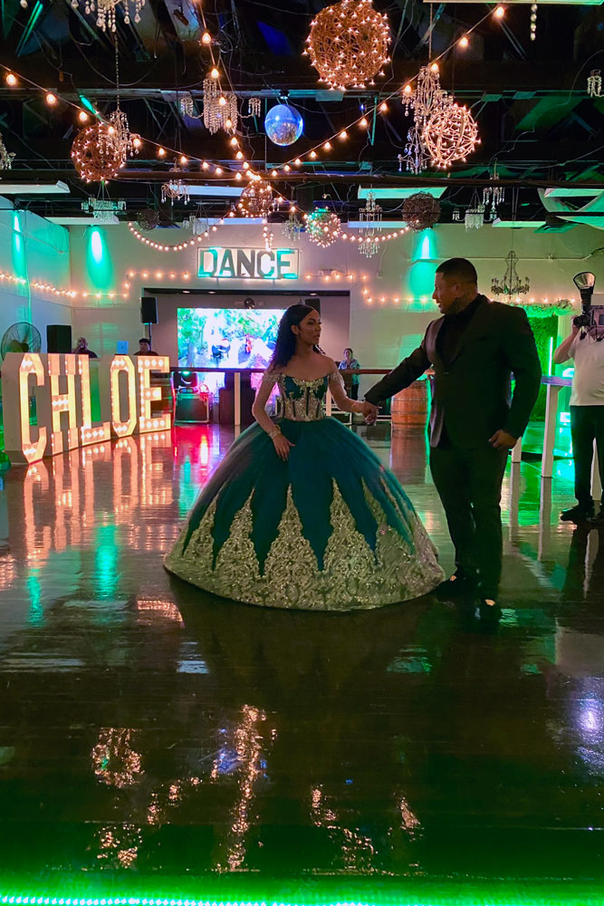 Quinceañera girl with father preparing for a first dance under the accent lights and on a shiny dance floor