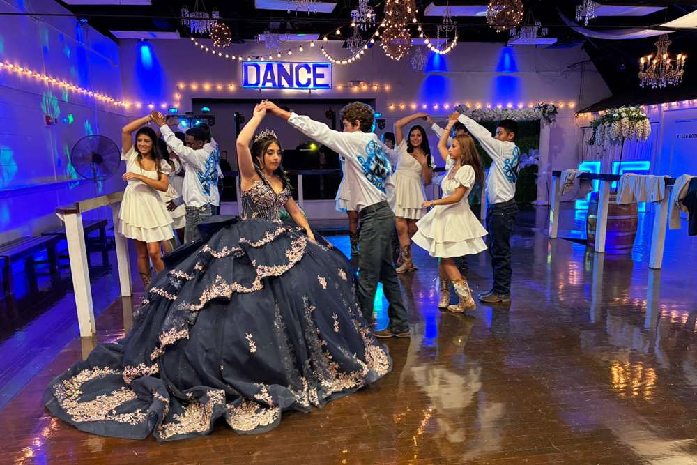 Quinceañera celebrating with her court on the illuminated dance floor.