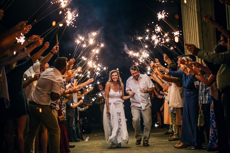 Bride and groom making their sparkler exit beneath the illuminated portico.