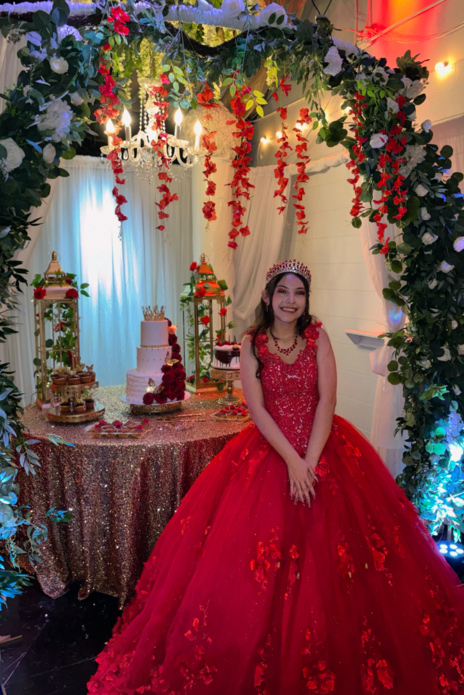 Quinceañera taking a photo op monent in front ofthe  beautiful cake table at a Fort Worth event venue
