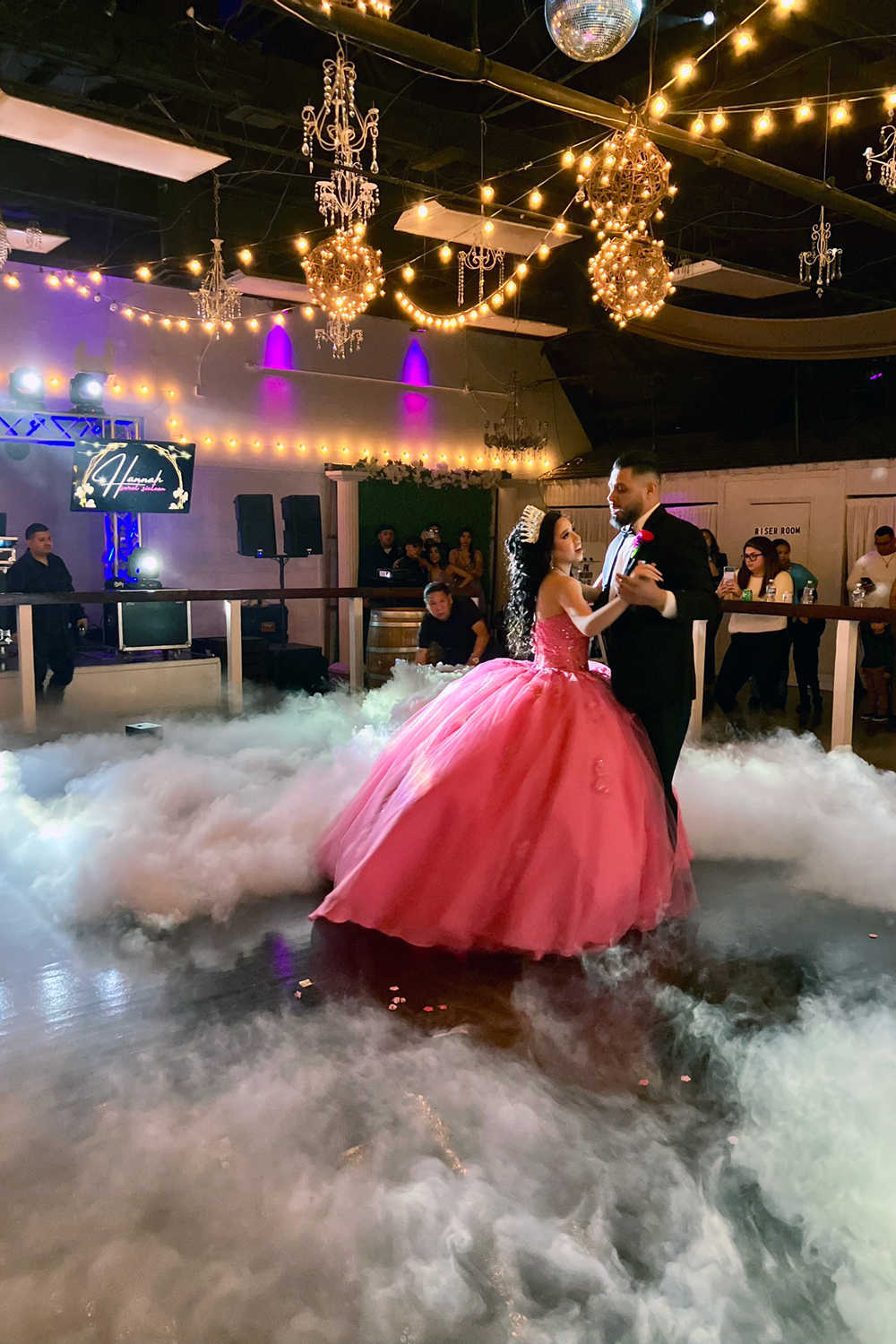 Quince girl in pink dress with father during their father/daughter dance and dancing on a lit ballroom dance floor with smokey fog.
