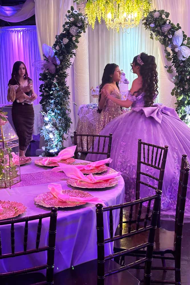 Guest arrival greeting the quince girl in front of the garden cake table.