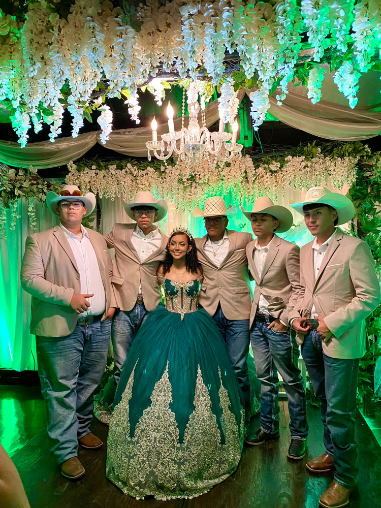 Quince girl surrounded by friends, greenery and warm lighting in a forest-themed setting