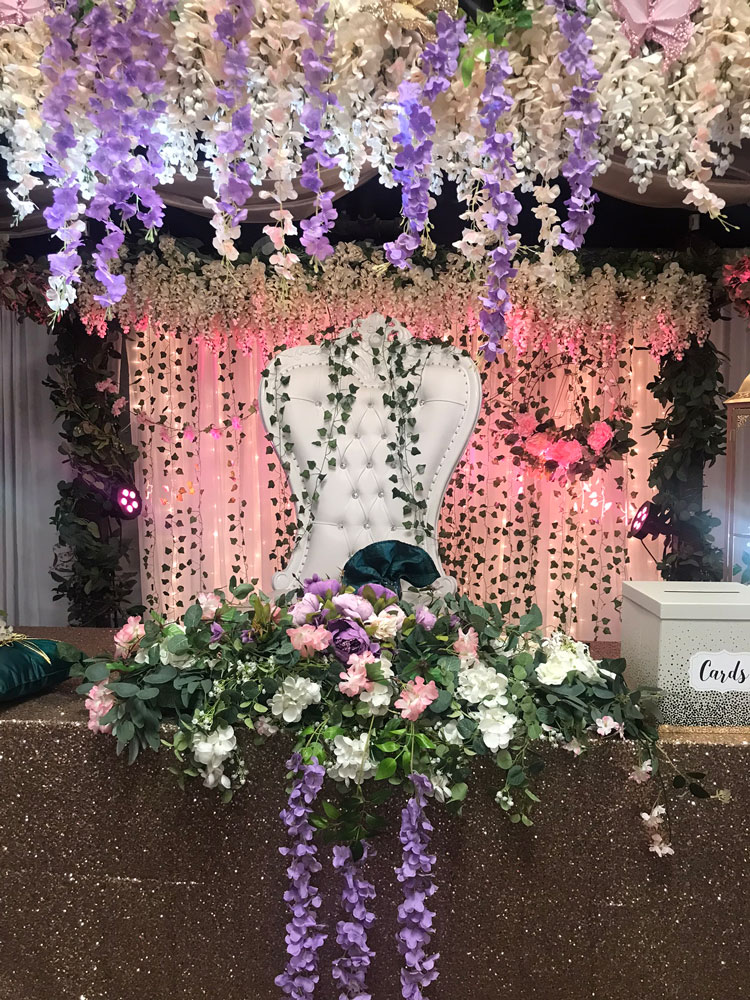 Head table decorated in enchanted forest shades with lush greenery and romantic lighting