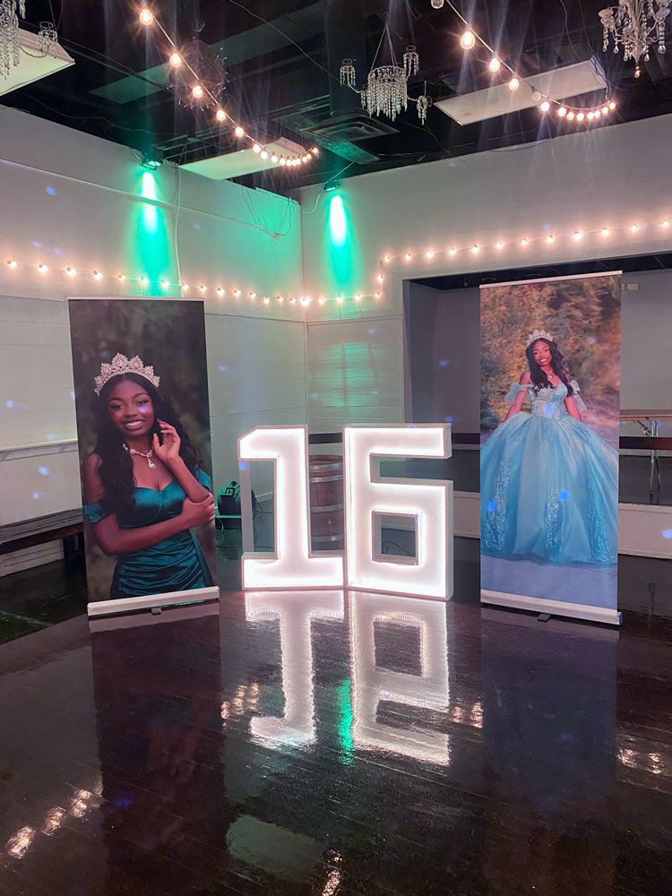 Sweet sixteen themed display on dance floor framed by emerald green uplighting