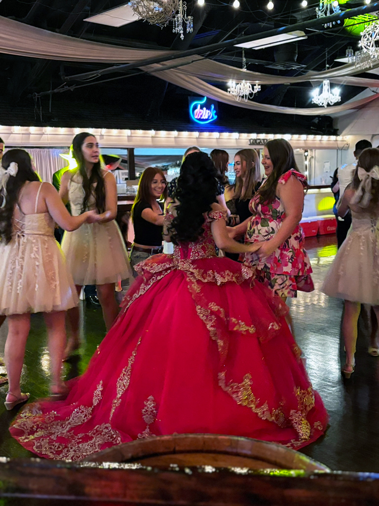 Quince girl sharing the dance floor beneath warm red lighting