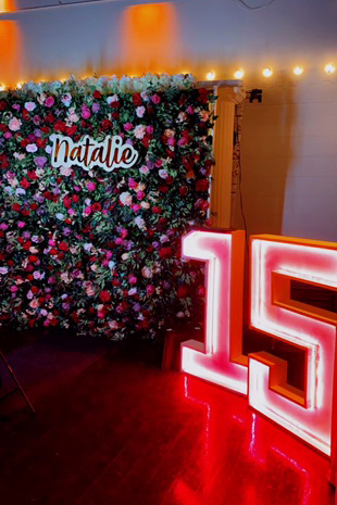 Floral photo op background with large lighted numbers styled in layered shades of red